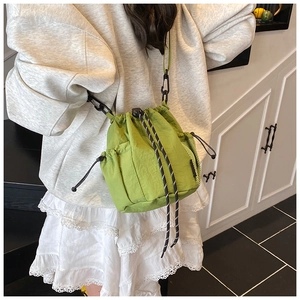 Detail of vibrant green bucket bag featuring thick bicolored drawstrings and mesh pocket
