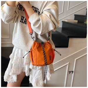 Detail view of orange drawstring bucket bag with side mesh pocket and adjustable strap