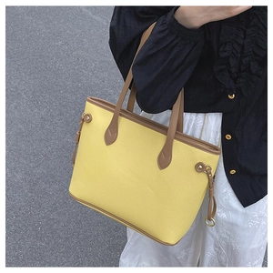 Detail of yellow lychee textured tote bag with brown straps and metal buckle accents