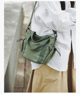 Detail of army green nylon crossbody bag with side drawstrings and adjustable strap