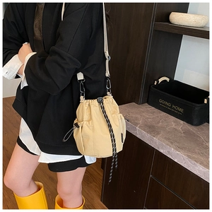 Close-up of khaki canvas bucket bag with drawstring closure and two front pockets