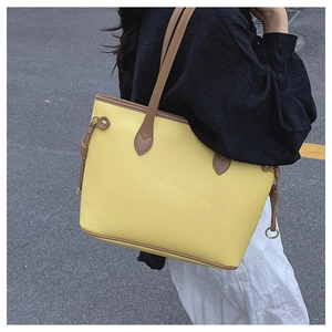Detail of yellow lychee leather tote bag with brown handles and gold ring accents