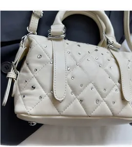 Dettaglio borsa beige trapuntata con strass sparsi e hardware argentato