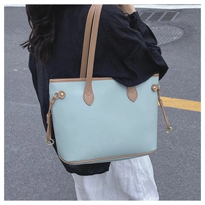 Detail of mint green lychee leather tote bag with brown contrast drawstrings and metal rings
