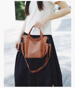 Outdoor shot of caramel nylon crossbody bag featuring side pockets and adjustable strap