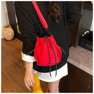 Detail of red drawstring canvas bucket bag with nylon strap on a female model