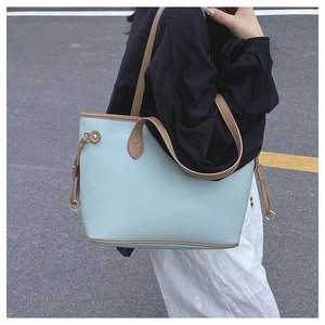 Detail of mint green tote bag with brown straps and side drawstring metal rings