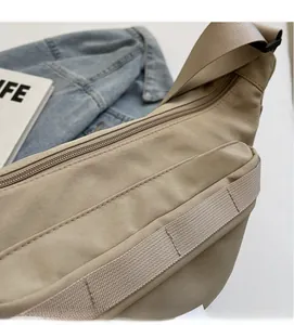 Gros plan du sac bandoulière beige en nylon montrant la texture et les détails du zip