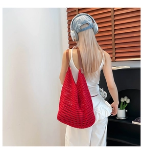 Close-up of red hollow crochet tote bag with brown leather handles and metal rivets