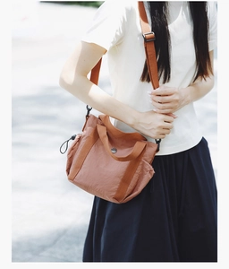 Detail of caramel nylon crossbody bag with drawstring sides and adjustable strap