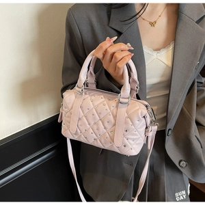 Close-up of pink quilted leather Boston bag with silver studs and cylindrical handles