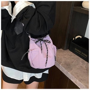 Close-up of purple nylon bucket bag with drawstring closure and black wide shoulder strap