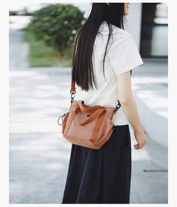 Detail of rust brown nylon crossbody bag with adjustable strap and drawstring side shown on model