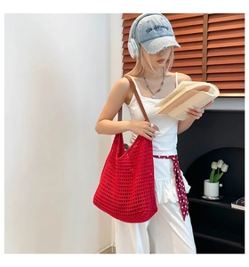 Detail of red hollow woven tote bag with brown leather straps on a white outfit