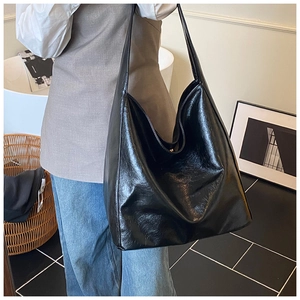 Detailed view of black glossy PU leather hobo bag worn as a spacious shoulder tote