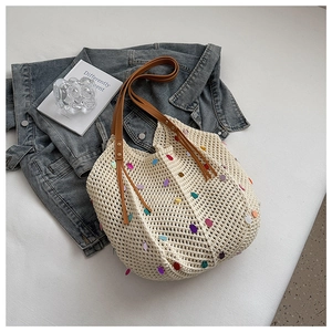 Detail of cream woven tote bag with colorful sequins and brown leather tassel handle