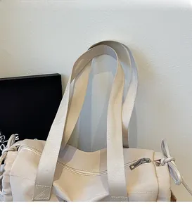 Dettaglio della tracolla larga e cerniera metallica sulla borsa tote in tela beige