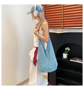 Detailed view of light blue hollow knit tote bag worn over shoulder for summer beach use