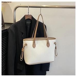 Detail of off-white lychee texture tote bag with brown leather trim and metal ring accents