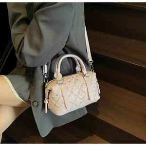 Detail of light pink quilted bucket bag with crystal studs and silver hardware