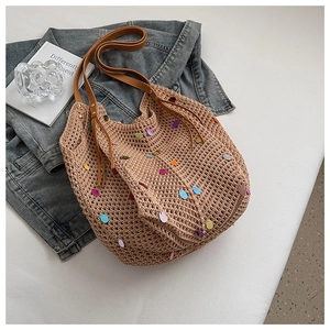 Detail of beige knit tote bag featuring vibrant sequins and brown leather handles
