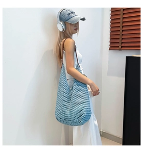Detail of light blue hollow woven tote bag with slim brown shoulder straps for beach