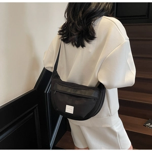 Mannequin portant un sac bandoulière croissant noir avec étiquette blanche sur escalier