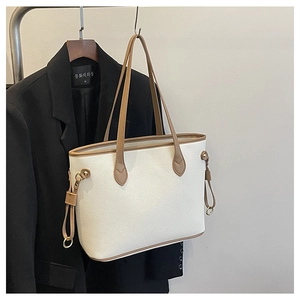 Detailed macro view of litchi-textured cream PU leather and gold-tone metal ring on tote bag