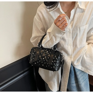 Detail of black quilted leather bucket bag with elegant pearl and diamond embellishments