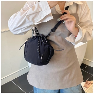 Close-up of black nylon drawstring bucket bag with adjustable strap and side label