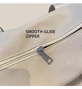 Dettaglio della cerniera in metallo argento su borsa tote in tela beige con cuciture fini