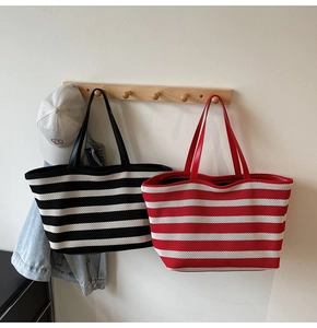 Detail of striped knitted tote bags in black and red hanging on wooden wall hooks