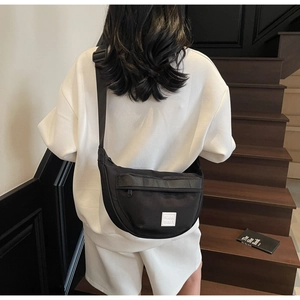 Vue arrière d'un sac bandoulière en nylon noir porté par un mannequin en escalier