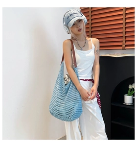 Detail of blue crochet tote bag featuring wide mesh pattern and brown leather strap