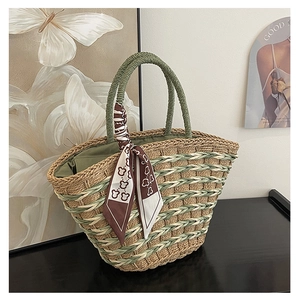 Detail of hand-woven straw tote with green accent pattern and decorative bear print scarf