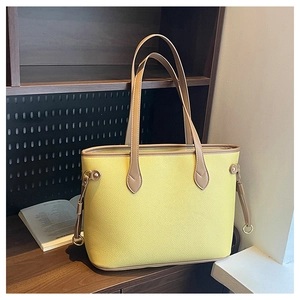 Close-up of a yellow pebbled leather tote bag with brown handles and metal ring charms