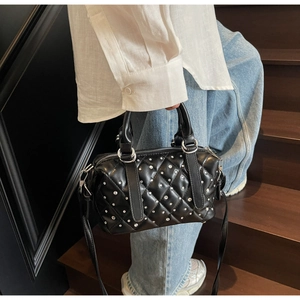 Detail view of quilted black crossbody bag with silver studs on elegant wooden stairs