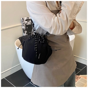 Detailed view of black canvas bucket bag with braided drawstring and chain strap