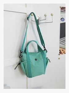 Detail of mint green nylon bag showing drawstring side pockets and adjustable strap