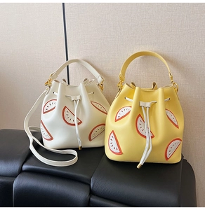 Detail of white and yellow bucket bags with citrus embroidery on a black leather seat