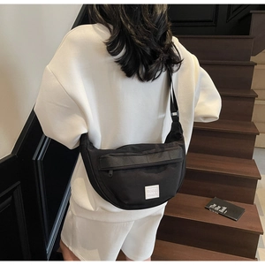 Détail du sac demi-lune en nylon noir avec bandoulière réglable et logo sur le mannequin