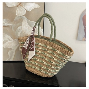 Detail of woven straw handbag with green handles and a bear pattern brown silk scarf