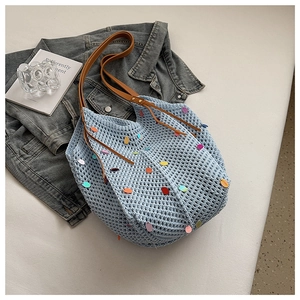 Detail of light blue crochet tote bag featuring colorful sequins and brown leather handle