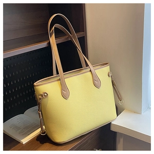 Detail of yellow lychee texture tote bag with brown straps and gold metal ring accent