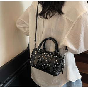 Detail of black quilted leather bucket bag with silver studs worn by a model