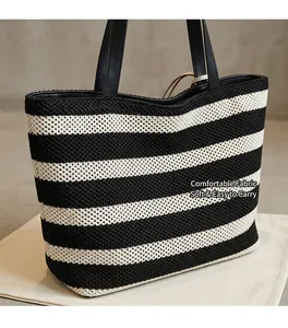 Detail of black and white striped knit tote bag with zipper and leather shoulder strap