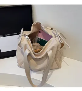 Dettaglio dell'interno capiente di una borsa tote in tela beige con un tablet rosa dentro