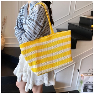 Vue détaillée du sac cabas tissé rayé avec texture en maille et longues anses en jaune et blanc