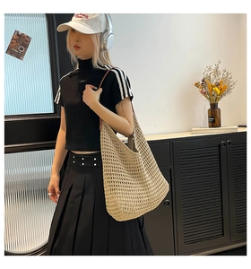 Close-up of beige woven cotton shoulder bag with elegant hollow knit design and brown leather straps