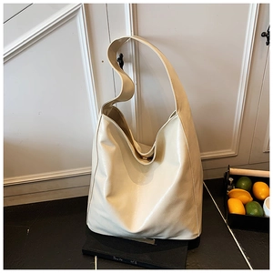 Detail of a large cream-colored PU leather tote bag with magnetic closure and wide strap